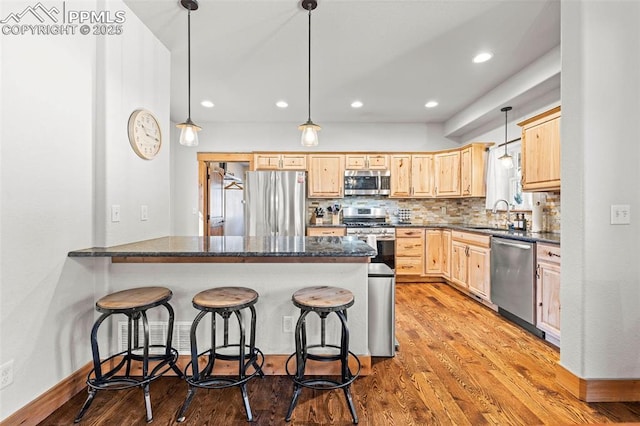 404 S Willow St, Woodland Park, CO 80863 - kitchen featuring stainless steel appliances, light brown cabinetry, a peninsula, a kitchen breakfast bar, and a sink