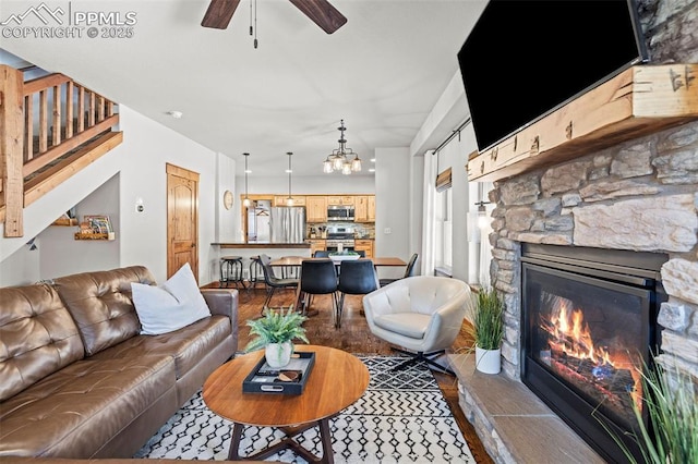 404 S Willow St, Woodland Park, CO 80863 - living area with dark wood-type flooring, a ceiling fan, stairway, a stone fireplace, and a chandelier