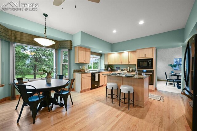 8110 Routt Ct, Colorado Springs, CO 80919 - kitchen with black appliances, light brown cabinets, a center island with sink, light wood-style flooring, and recessed lighting