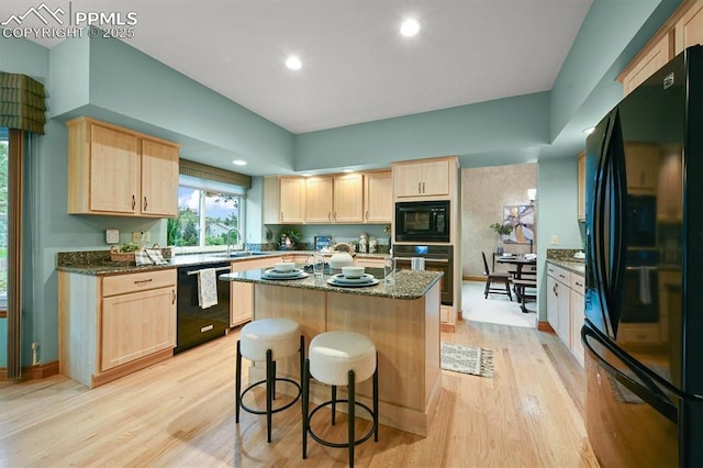 8110 Routt Ct, Colorado Springs, CO 80919 - kitchen with black appliances, light brown cabinetry, light wood-style flooring, dark stone counters, and recessed lighting