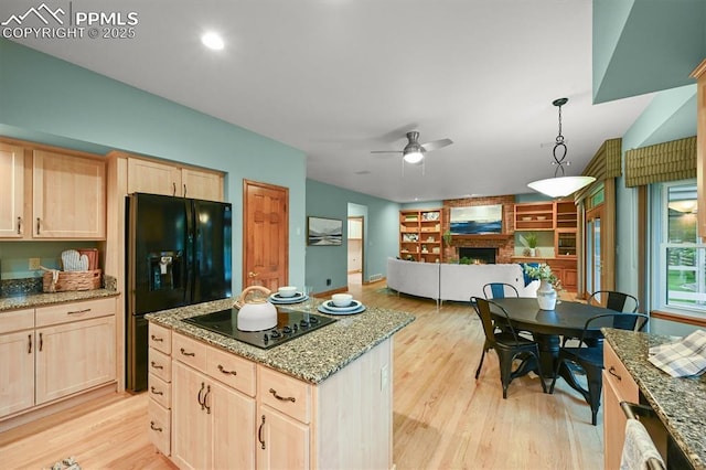 8110 Routt Ct, Colorado Springs, CO 80919 - kitchen featuring light brown cabinets, black appliances, light wood-style flooring, and a brick fireplace