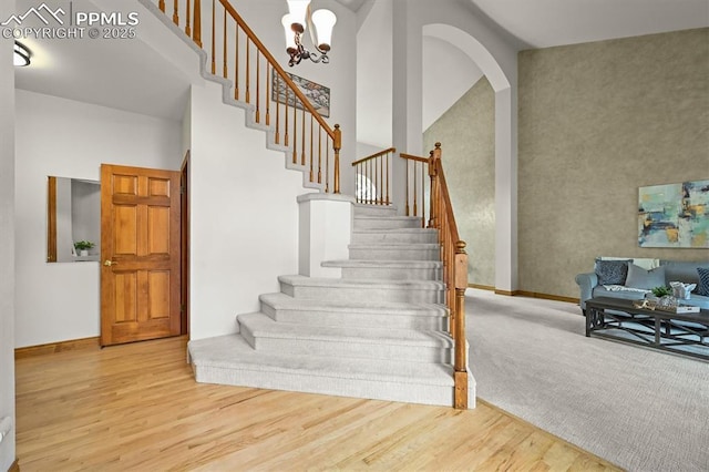 8110 Routt Ct, Colorado Springs, CO 80919 - staircase featuring wood finished floors, a high ceiling, and a chandelier