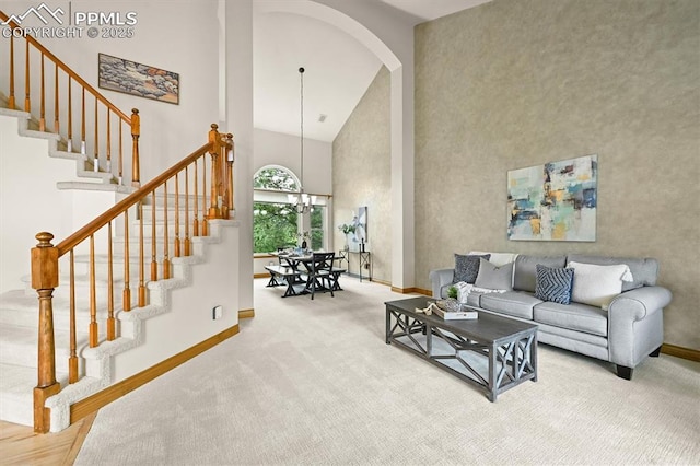 8110 Routt Ct, Colorado Springs, CO 80919 - living room featuring high vaulted ceiling, stairs, arched walkways, carpet flooring, and a chandelier