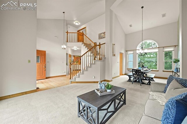 8110 Routt Ct, Colorado Springs, CO 80919 - living room featuring high vaulted ceiling, light carpet, a chandelier, and stairs