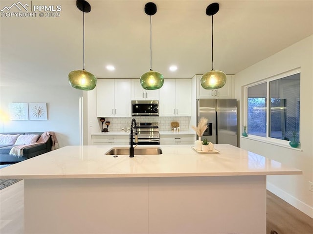 4770 Newton Dr, Colorado Springs, CO 80916 - kitchen with stainless steel appliances, a sink, tasteful backsplash, white cabinetry, and a kitchen island with sink