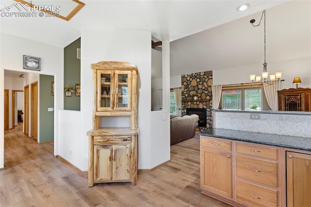 802 Red Eagle Ct, Woodland Park, CO 80863 - kitchen featuring lofted ceiling, light wood finished floors, a stone fireplace, a chandelier, and hanging light fixtures