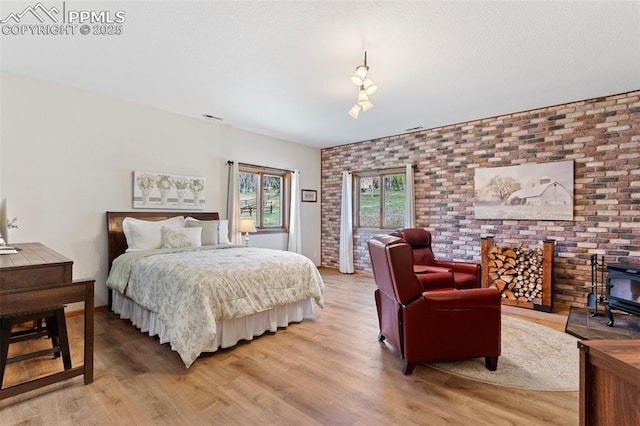 802 Red Eagle Ct, Woodland Park, CO 80863 - bedroom featuring a wood stove, light wood-style floors, and brick wall