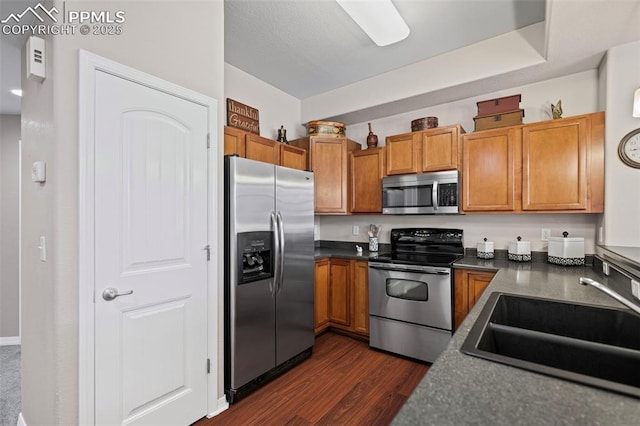 6678 Bethesda Pt Unit C, Colorado Springs, CO 80918 - kitchen featuring appliances with stainless steel finishes, dark countertops, dark wood-style flooring, and brown cabinetry