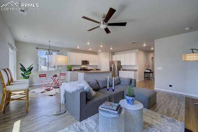 10144 Bluffstone Ct, Peyton, CO 80831 - living room featuring light wood-style flooring, a ceiling fan, baseboards, recessed lighting, and a chandelier