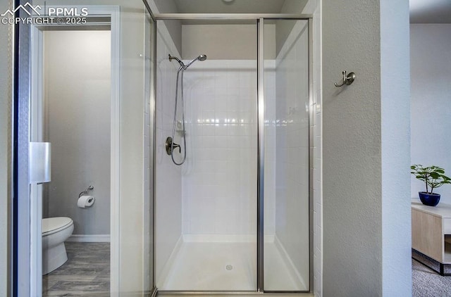10144 Bluffstone Ct, Peyton, CO 80831 - full bathroom with a stall shower, toilet, a textured wall, and wood finished floors