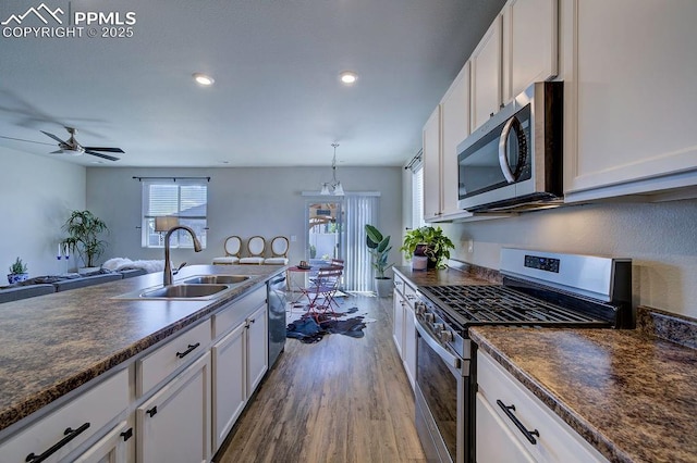 10144 Bluffstone Ct, Peyton, CO 80831 - kitchen with stainless steel appliances, a sink, dark countertops, dark wood-style floors, and white cabinets