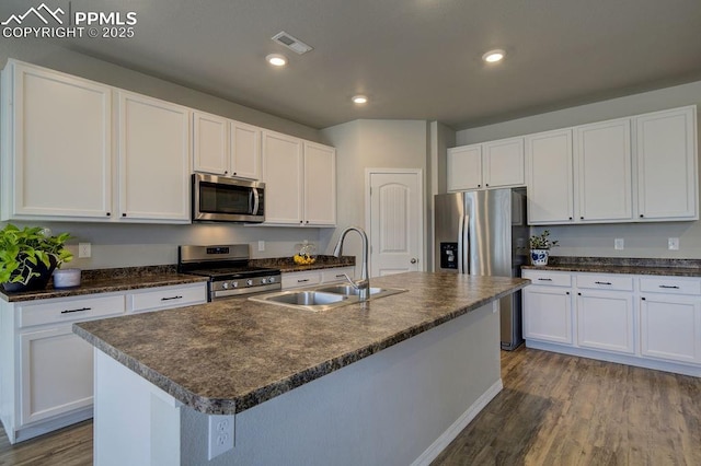 10144 Bluffstone Ct, Peyton, CO 80831 - kitchen with stainless steel appliances, a sink, wood finished floors, white cabinetry, and a center island with sink