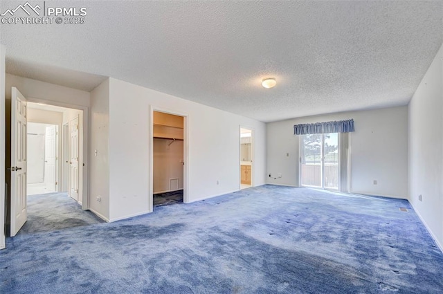 2609 Freedom Hts, Colorado Springs, CO 80904 - unfurnished bedroom featuring carpet floors, a textured ceiling, baseboards, a walk in closet, and connected bathroom