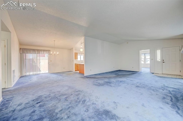 2609 Freedom Hts, Colorado Springs, CO 80904 - unfurnished living room featuring a chandelier, plenty of natural light, a textured ceiling, carpet floors, and lofted ceiling