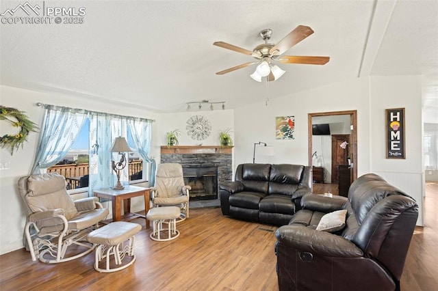 9180 S Rush Rd, Rush, CO 80833 - living room featuring wood finished floors, a ceiling fan, a fireplace, and rail lighting