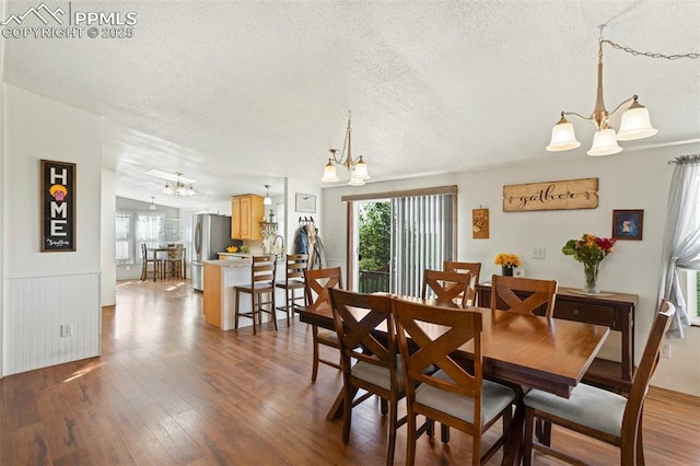 9180 S Rush Rd, Rush, CO 80833 - dining room featuring a chandelier, healthy amount of natural light, a textured ceiling, wood finished floors, and a wainscoted wall