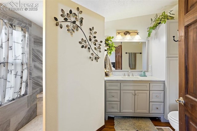 9180 S Rush Rd, Rush, CO 80833 - full bath featuring a tile shower, vanity, toilet, wood finished floors, and a textured ceiling
