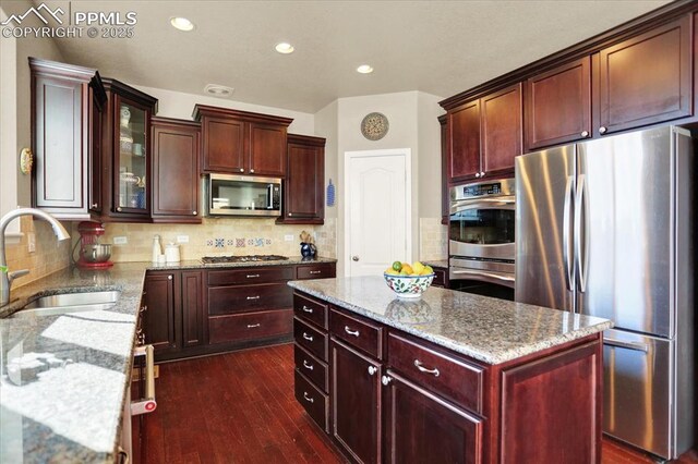 9773 Beryl Dr, Peyton, CO 80831 - kitchen with appliances with stainless steel finishes, a sink, a center island, light stone counters, and recessed lighting
