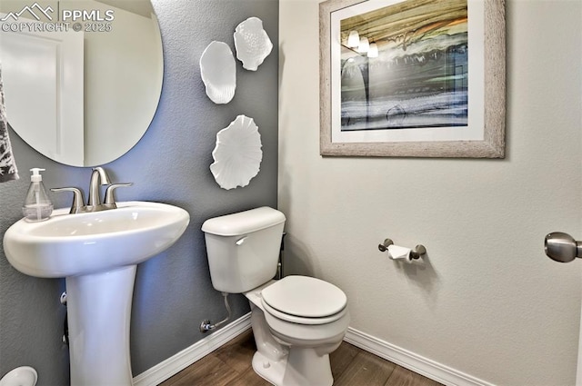 10811 Raylan Way, Falcon, CO 80831 - bathroom with baseboards, toilet, wood finished floors, and a sink