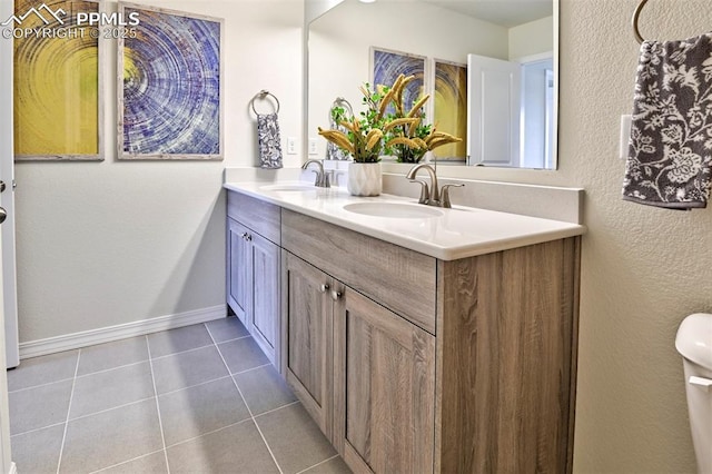 10811 Raylan Way, Falcon, CO 80831 - bathroom with double vanity, tile patterned floors, toilet, baseboards, and a textured wall