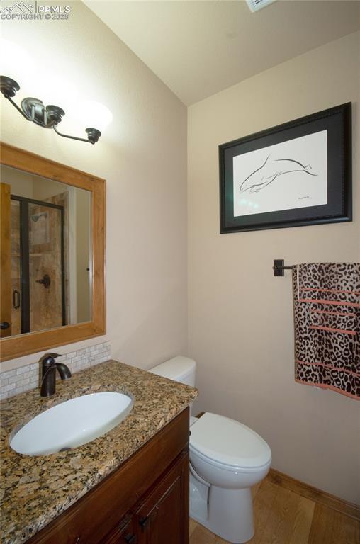 797 Forest View Way, Monument, CO 80132 - full bath featuring vanity, toilet, wood finished floors, a shower with door, and baseboards