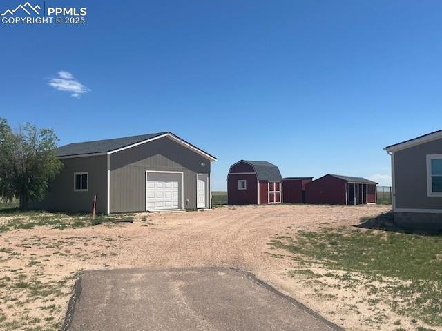 20150 Enoch Rd, Colorado Springs, CO 80930 - view of side of property featuring a detached garage, an outbuilding, and driveway