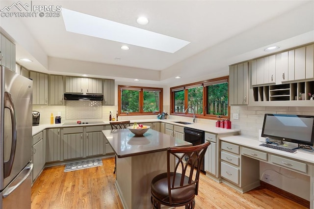 720 Popes Valley Dr, Colorado Springs, CO 80919 - kitchen with black appliances, a skylight, under cabinet range hood, a sink, and backsplash