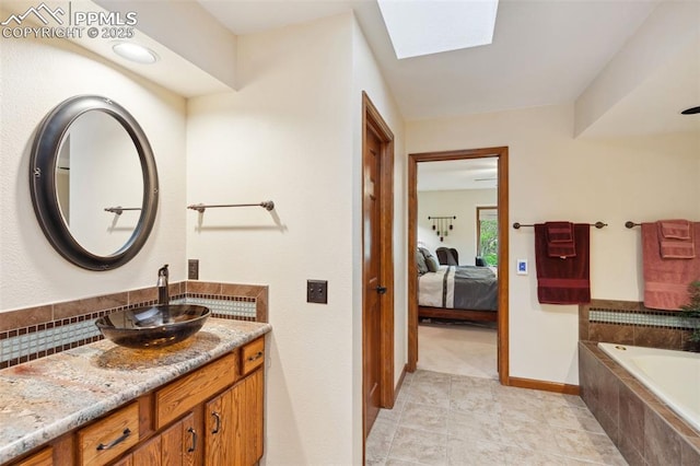720 Popes Valley Dr, Colorado Springs, CO 80919 - ensuite bathroom featuring a skylight, vanity, a relaxing tiled tub, tile patterned flooring, and baseboards