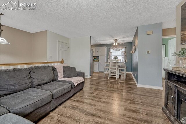 7108 Chippewa Rd, Colorado Springs, CO 80915 - living room with wood finished floors, ceiling fan, a glass covered fireplace, and a textured ceiling
