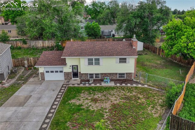7108 Chippewa Rd, Colorado Springs, CO 80915 - view of front facade with driveway, a garage, stone siding, a fenced backyard, and a chimney