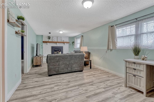 7108 Chippewa Rd, Colorado Springs, CO 80915 - living room featuring a textured ceiling, light wood-style flooring, and a fireplace