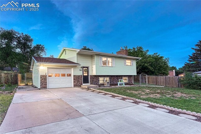 7108 Chippewa Rd, Colorado Springs, CO 80915 - split level home featuring an attached garage, concrete driveway, a chimney, and stone siding