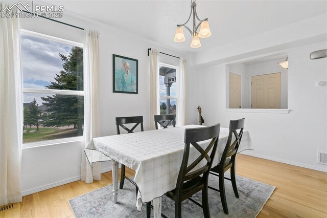 7711 Menagerie Ln, Colorado Springs, CO 80923 - dining room featuring a chandelier, wood finished floors, and baseboards