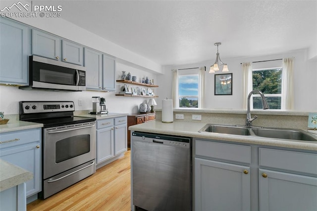 7711 Menagerie Ln, Colorado Springs, CO 80923 - kitchen featuring stainless steel appliances, a sink, light countertops, pendant lighting, and light wood-style floors