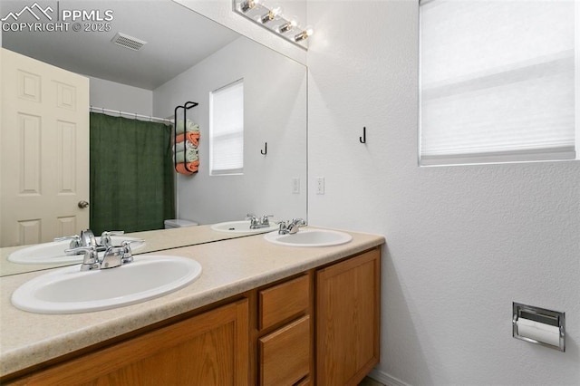 7711 Menagerie Ln, Colorado Springs, CO 80923 - bathroom with double vanity, curtained shower, and toilet