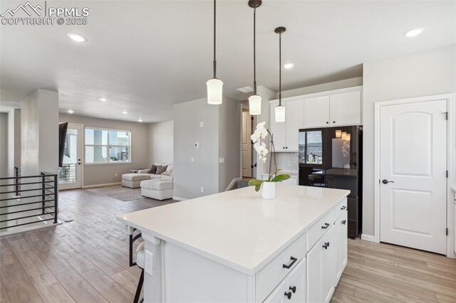 10671 Larimar Pt, Colorado Springs, CO 80905 - kitchen with light wood-style floors, a center island, white cabinetry, decorative light fixtures, and light countertops