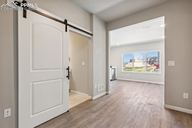 10671 Larimar Pt, Colorado Springs, CO 80905 - foyer entrance with a barn door, light wood finished floors, and baseboards