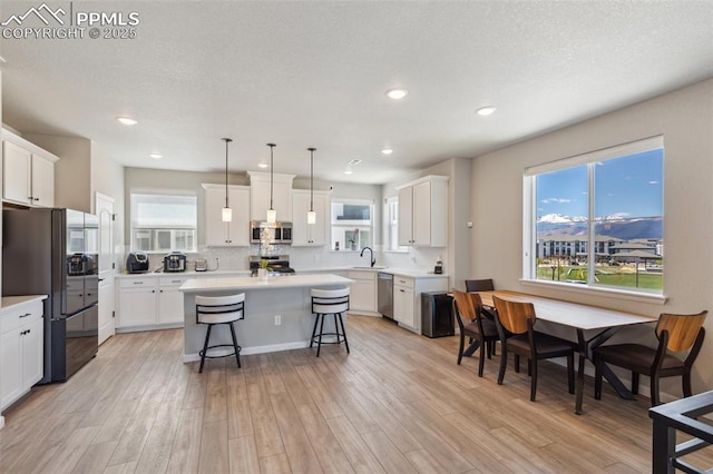 10671 Larimar Pt, Colorado Springs, CO 80905 - kitchen featuring appliances with stainless steel finishes, a sink, a breakfast bar area, a kitchen island, and light wood-style floors