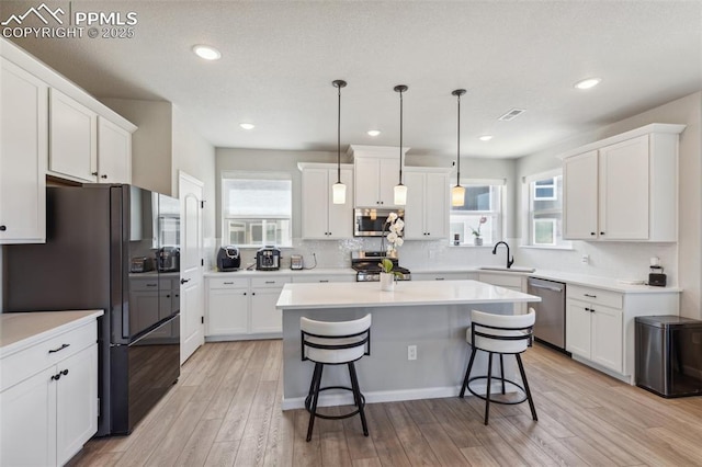 10671 Larimar Pt, Colorado Springs, CO 80905 - kitchen featuring appliances with stainless steel finishes, a sink, a breakfast bar area, white cabinetry, and recessed lighting