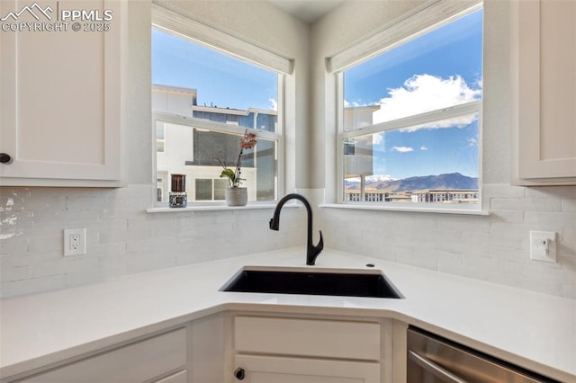 10671 Larimar Pt, Colorado Springs, CO 80905 - kitchen with a sink, dishwasher, tasteful backsplash, white cabinets, and light countertops