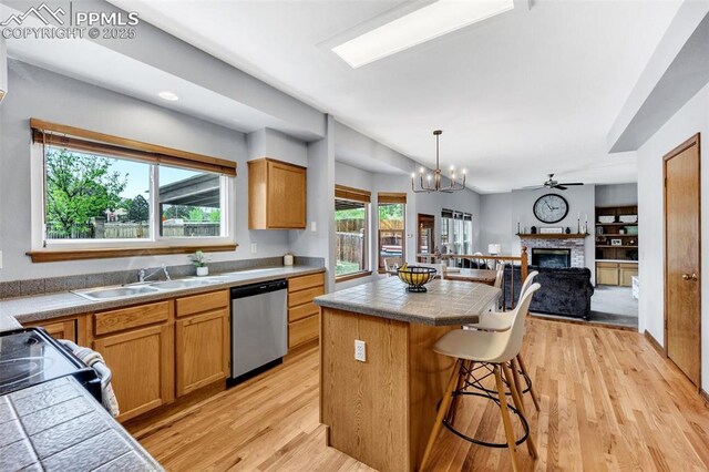 6390 Moccasin Pass Ct, Colorado Springs, CO 80919 - kitchen featuring dishwasher, a kitchen island, a kitchen bar, a sink, and a fireplace