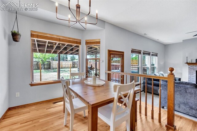 6390 Moccasin Pass Ct, Colorado Springs, CO 80919 - dining area with wood finished floors, baseboards, a chandelier, and a fireplace