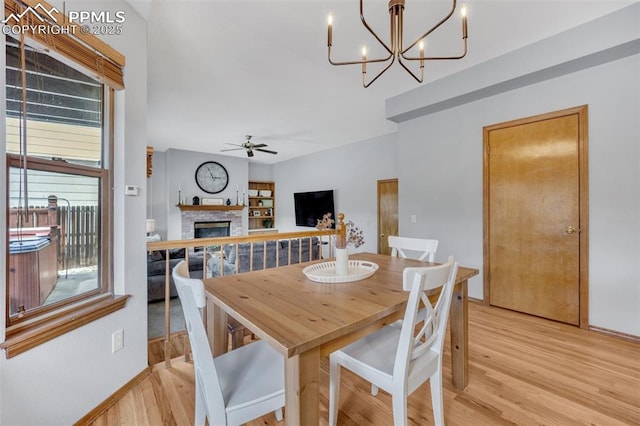 6390 Moccasin Pass Ct, Colorado Springs, CO 80919 - dining area with a ceiling fan, light wood-style floors, a fireplace, and a chandelier