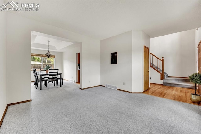 6390 Moccasin Pass Ct, Colorado Springs, CO 80919 - carpeted living area with baseboards, stairs, a raised ceiling, and a chandelier