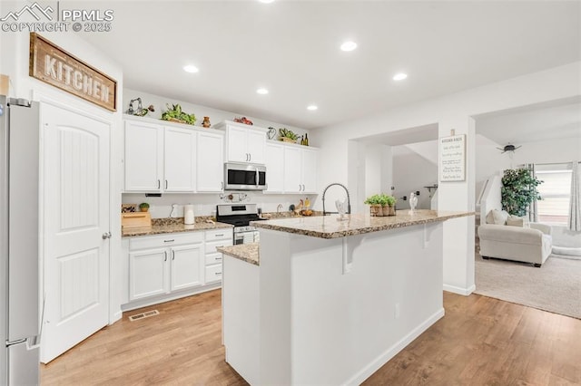 10140 Seawolf Dr, Colorado Springs, CO 80925 - kitchen with appliances with stainless steel finishes, light wood-style flooring, a kitchen bar, recessed lighting, and white cabinets