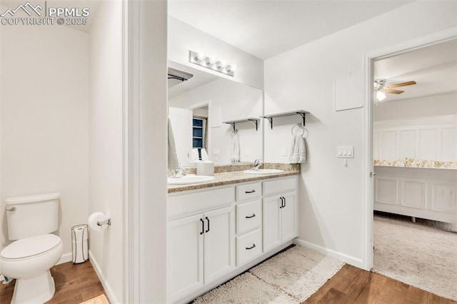 10140 Seawolf Dr, Colorado Springs, CO 80925 - bathroom with double vanity, wood finished floors, a ceiling fan, toilet, and baseboards