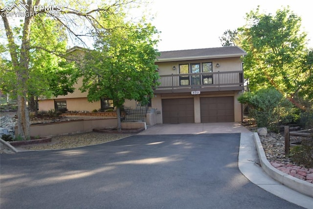 view of front facade featuring asphalt driveway, stucco siding, a garage, and a balcony