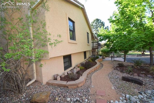 view of side of property with stucco siding and a balcony