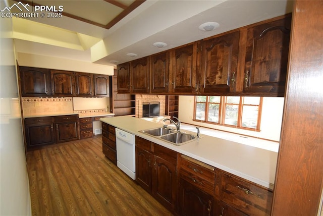 kitchen featuring dishwasher, a sink, dark wood finished floors, light countertops, and tasteful backsplash