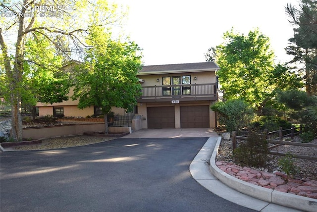 view of front of home with asphalt driveway, an attached garage, stucco siding, and a balcony